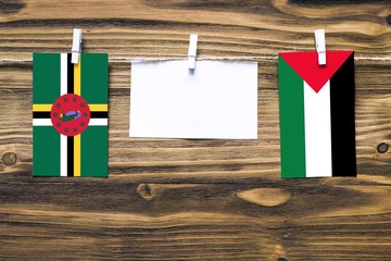 Hanging flags of Dominica and Palestine attached to rope with clothes pins with copy space on white...