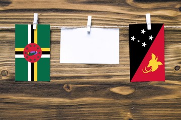 Hanging flags of Dominica and Papua New Guinea attached to rope with clothes pins with copy space...