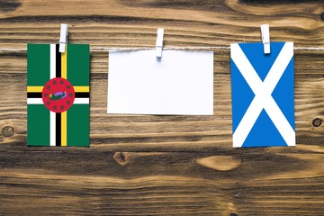 Hanging flags of Dominica and Scotland attached to rope with clothes pins with copy space on white...