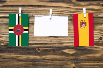 Hanging flags of Dominica and Spain attached to rope with clothes pins with copy space on white...