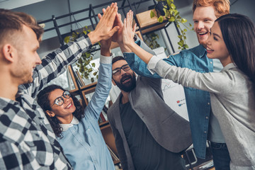 Startupers working at office together standing giving high five success