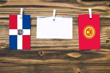 Hanging flags of Dominican Republic and Kyrgyzstan attached to rope with clothes pins with copy...