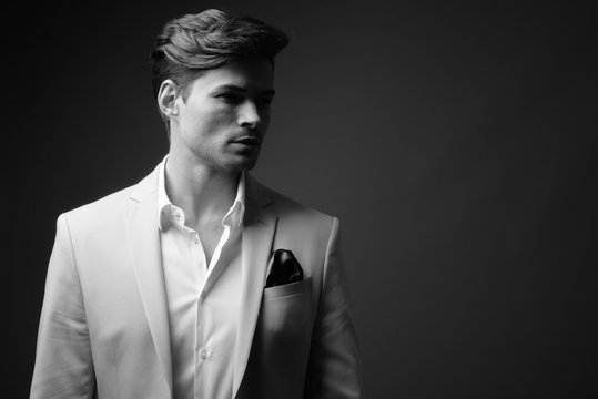 Portrait of young handsome businessman wearing suit in black and white