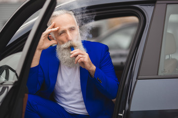 Old stylish man in the luxury car. Male with beard and mustash driving automobile. car sales salon.