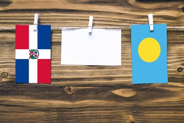 Hanging flags of Dominican Republic and Palau attached to rope with clothes pins with copy space on...