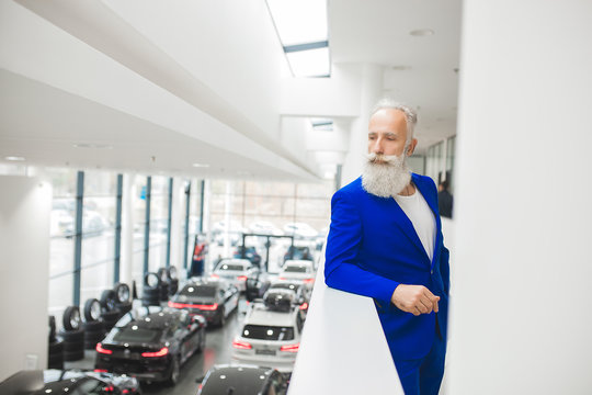Old stylish man in the luxury car. Male with beard and mustash driving automobile. car sales salon.