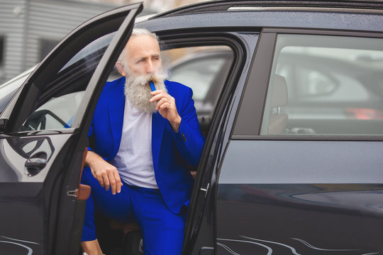 Old stylish man in the luxury car. Male with beard and mustash driving automobile. car sales salon.