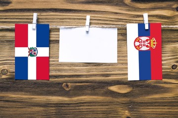Hanging flags of Dominican Republic and Serbia attached to rope with clothes pins with copy space...
