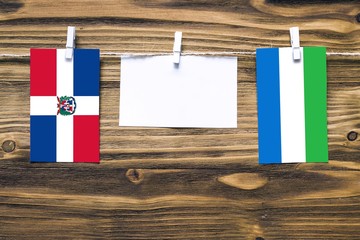 Hanging flags of Dominican Republic and Sierra Leone attached to rope with clothes pins with copy...