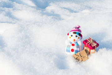 funny toy snowman with gifts in a snowdrift with a copy of space