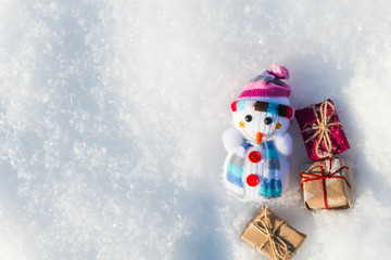 funny toy snowman with gifts in a snowdrift with a copy of space