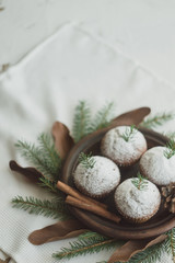 Christmas wreath imitation with a plate of cupcakes. Dessert decorated with fir branches and cones on a white background.