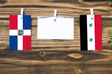 Hanging flags of Dominican Republic and Syria attached to rope with clothes pins with copy space on...