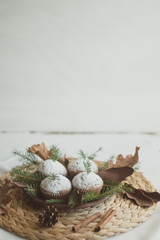 Christmas cupcakes on a straw wicker stand. Cupcakes decorated with fir branches and cones.