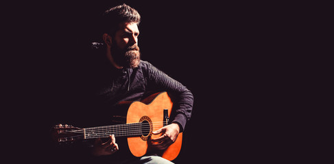 Bearded man playing guitar, holding an acoustic guitar in his hands. Music concept. Bearded...