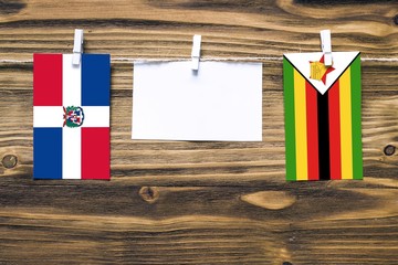 Hanging flags of Dominican Republic and Zimbabwe attached to rope with clothes pins with copy space...
