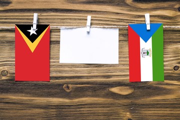 Hanging flags of East Timor and Equatorial Guinea attached to rope with clothes pins with copy...