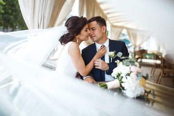 Young bride and groom in a cafe. Husband and wife hold each other's hands. Loving couple in a...