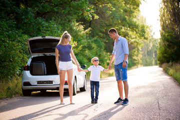 Young family travels by car. Dad, mom and son take a break from driving a car and walk.