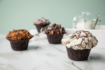 Muffin Auswahl mit Blaubeeren, Walnuss, Haselnuss und Weiße Schokolade mit Milch und Zucker für Kaffeepause auf Marmor Tisch und Grün Hintergrund
