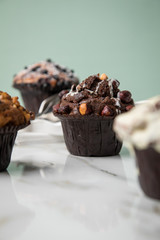 Muffin Auswahl mit Blaubeeren, Walnuss, Haselnuss und Weiße Schokolade für Kaffeepause auf Marmor Tisch und Grün Hintergrund