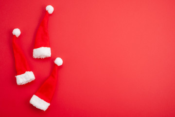 Festive christmas decoration with red Santa hats over red background