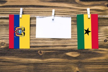 Hanging flags of Ecuador and Ghana attached to rope with clothes pins with copy space on white note...