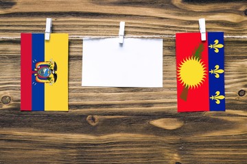 Hanging flags of Ecuador and Guadeloupe attached to rope with clothes pins with copy space on white...
