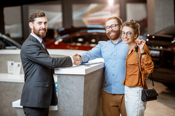 Sales manager with a young couple buying a new car