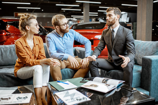 Young couple with saller on the couch at the car dealership
