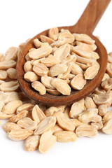 Roasted unsalted shelled peanuts on wooden spoon. Isolated on white background. Macro.