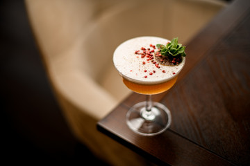 Delicious alcoholic cocktail in the glass decorated with a mint leaf branch, red peppercorns and...