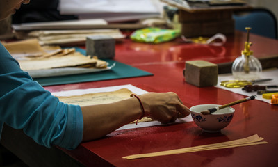 Traditional Chinese book and calligraphy restorer laboratory. Master hands at work close-up.