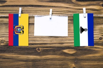 Hanging flags of Ecuador and Lesotho attached to rope with clothes pins with copy space on white...