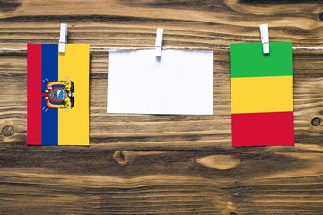 Hanging flags of Ecuador and Mali attached to rope with clothes pins with copy space on white note...