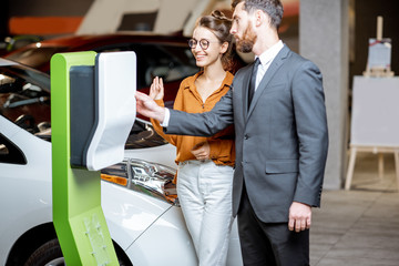 Sales manager with client near the car charging station in the showroom