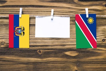 Hanging flags of Ecuador and Namibia attached to rope with clothes pins with copy space on white...