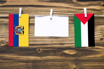 Hanging flags of Ecuador and Palestine attached to rope with clothes pins with copy space on white...