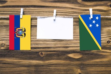 Hanging flags of Ecuador and Solomon Islands attached to rope with clothes pins with copy space on...