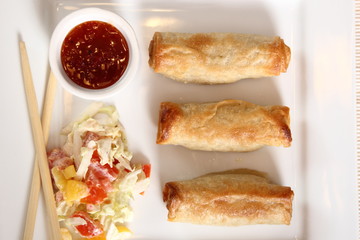 Spring roll with salad and chili sauce on plate