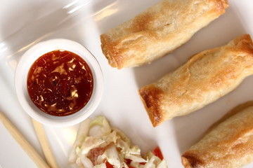 Spring roll with salad and chili sauce on plate