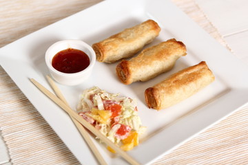 Spring roll with salad and chili sauce on plate