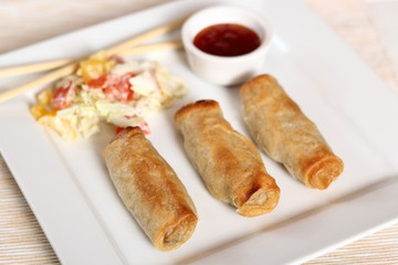 Spring roll with salad and chili sauce on plate