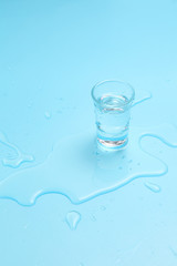 Vodka in shot glass on blue background with a blank space for a text, Russian vodka on color table