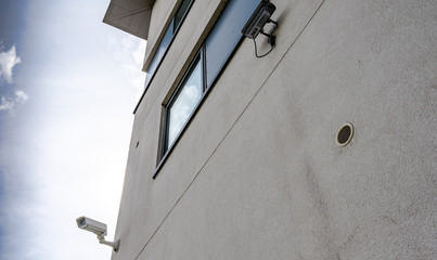Newly installed CCTV camera system seen on the side of a large, well-known UK hotel chain, looking towards the car park. A hotel room window is also visible.