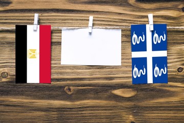 Hanging flags of Egypt and Martinique attached to rope with clothes pins with copy space on white note paper on wooden background.Diplomatic relations between countries.