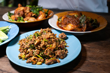 Spicy food in wood table such as Duck minced salad, Deep fried chicken, Stir fried fish with red chili paste on wood table. Thai traditional yummy food style dining table.