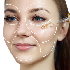 Young woman with lifting arrows on face applying primer oil.