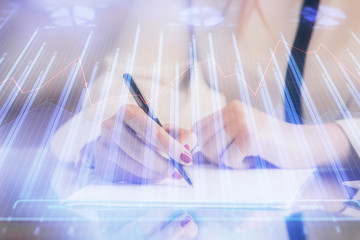 Double exposure of hands making notes with forex chart huds. Stock market concept.