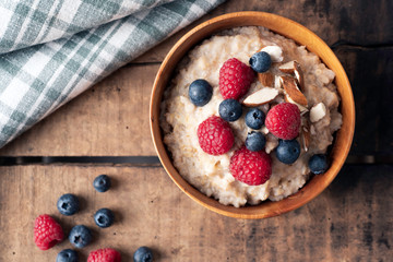 Flat lay food photography shoot of wheat porridge with blueberries and raspberries and almonds on top. Rustic theme. Healthy food and lifestyle concept.
